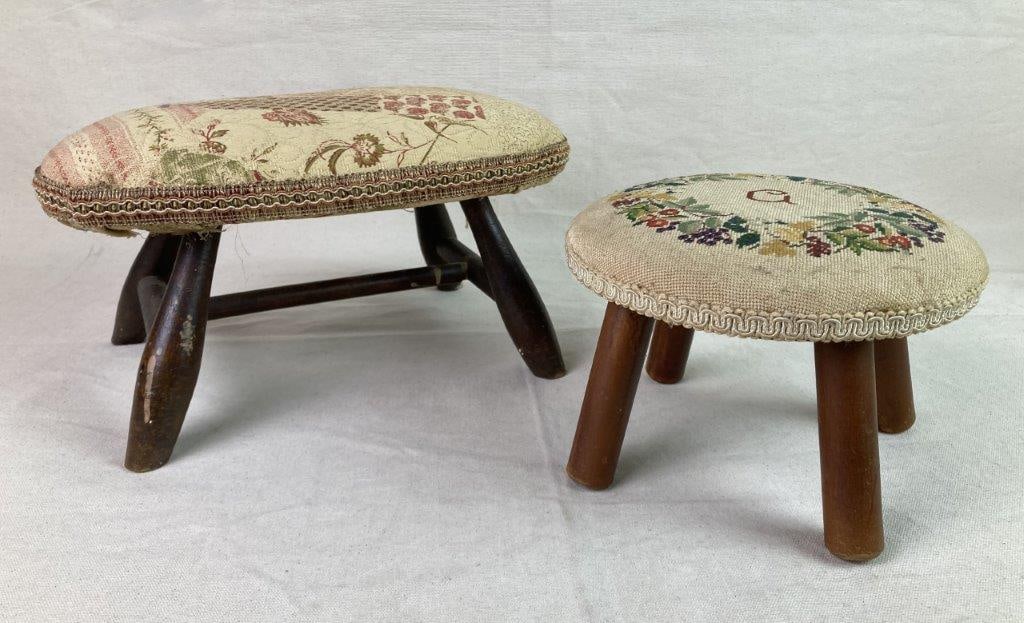 Two Vintage Victorian Style Footstools: A pair of Victorian-style footstools with turned wooden legs. The smaller example features needlepoint upholstery worked with a floral and fruit motif surrounding the letter