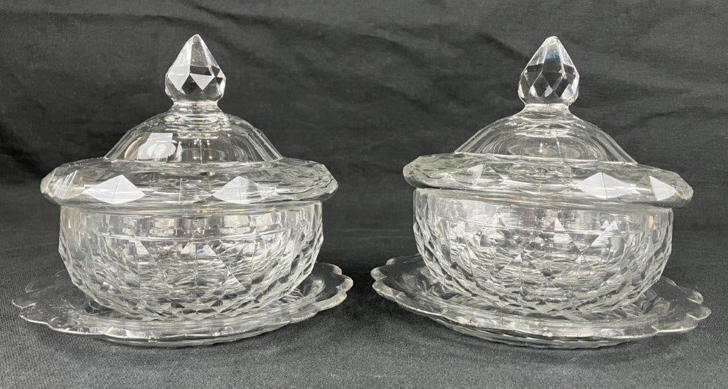 Pair of Crystal Candy Dishes: A pair of crystal candy dishes with faceted forms, each resting on a scalloped underplate. One example with its underplate measures approximately 7â€³ H x 6â€³ in