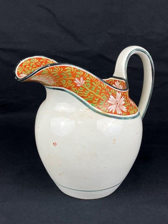 Early English Pitcher: An early English pitcher of robust yet graceful form, featuring hand-painted floral decoration along the rim and a delicately curved handle. Possibly from the Leeds region. Measures approximately
