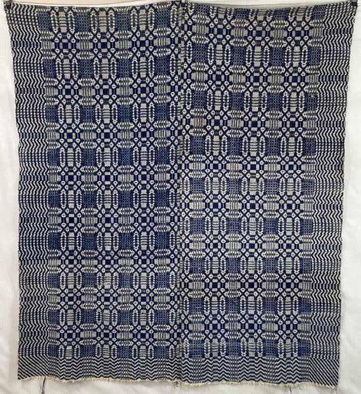Jacquard Woven Coverlet: An antique Jacquard woven coverlet featuring complex geometric patterns rendered in rich blue tones. The intricate design reflects the technical sophistication of early mechanized textile production