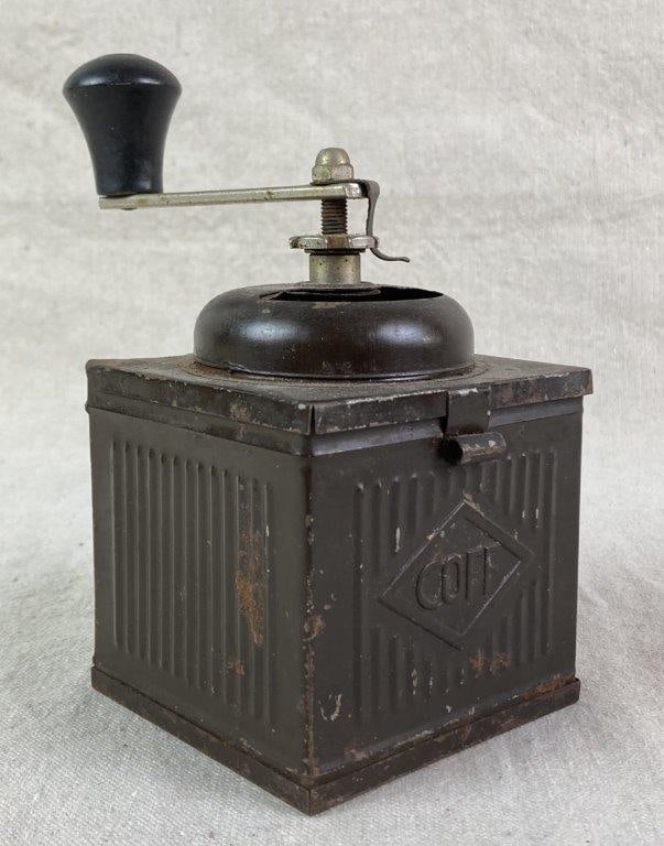 Antique Tin Coffee Grinder: An antique tin coffee grinder by COFF, featuring a cube-shaped tin body with ribbed texture, a domed top, and a hand crank. Exhibits a worn, aged patina from use. Measures approximately 6 1/2″