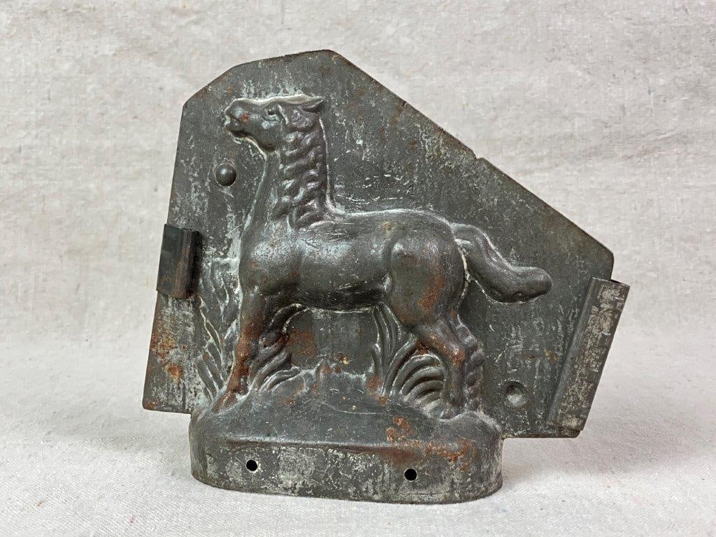 Early 20th Century Horse Chocolate Mold: An early 20th century tin chocolate mold in the form of a horse, constructed as a two-part mold. The surface retains a worn, aged patina that enhances its utilitarian charm and period appeal. Measures