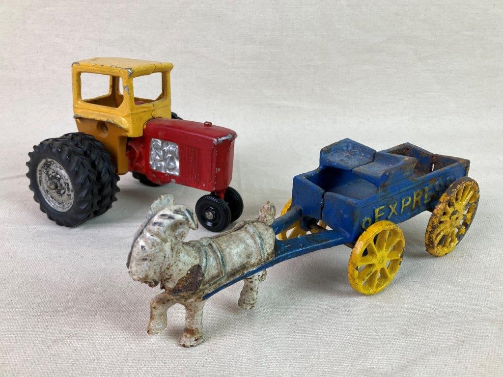 Vintage Toy Tractor and Goat-Pulled Cart: A charming vintage toy grouping featuring a yellow and red die-cast metal tractor with rubber wheels and silver-painted details, accompanied by a blue and yellow cast iron goat-drawn wagon marked 