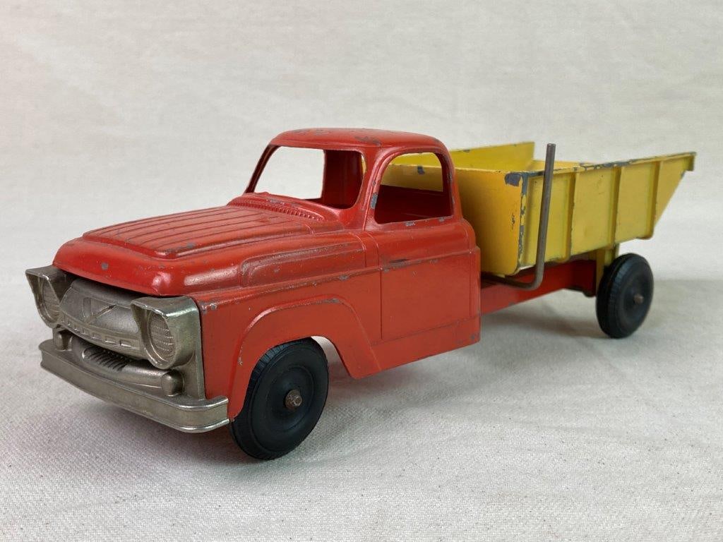 Vintage Hubley 470-58 Dump Truck Toy: A red and yellow die-cast metal dump truck toy made by Hubley, model number 470-58 embossed on the underside. Features a working lift-and-tilt dump bed. Exhibits a worn, aged patina. Measures
