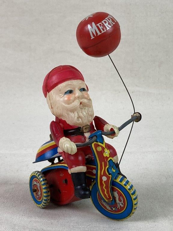 Vintage Suzuki Santa Tricycle Toy: A festive vintage wind-up toy by Suzuki, featuring a Santa Claus figure riding a tin and celluloid lithographed tricycle. Includes a balloon reading “Merry Christmas.” Made in Japan and