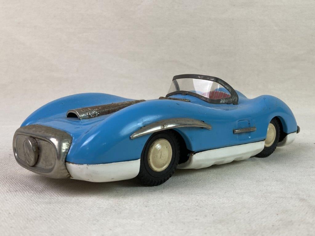 Vintage Asahi Tin Mercedes Toy Car: A blue tin lithographed Mercedes toy car manufactured by Asahi in Japan, featuring a Mercedes medallion to the front, detailed lithography, and rubber wheels. Exhibits an aged patina. Measures approxi