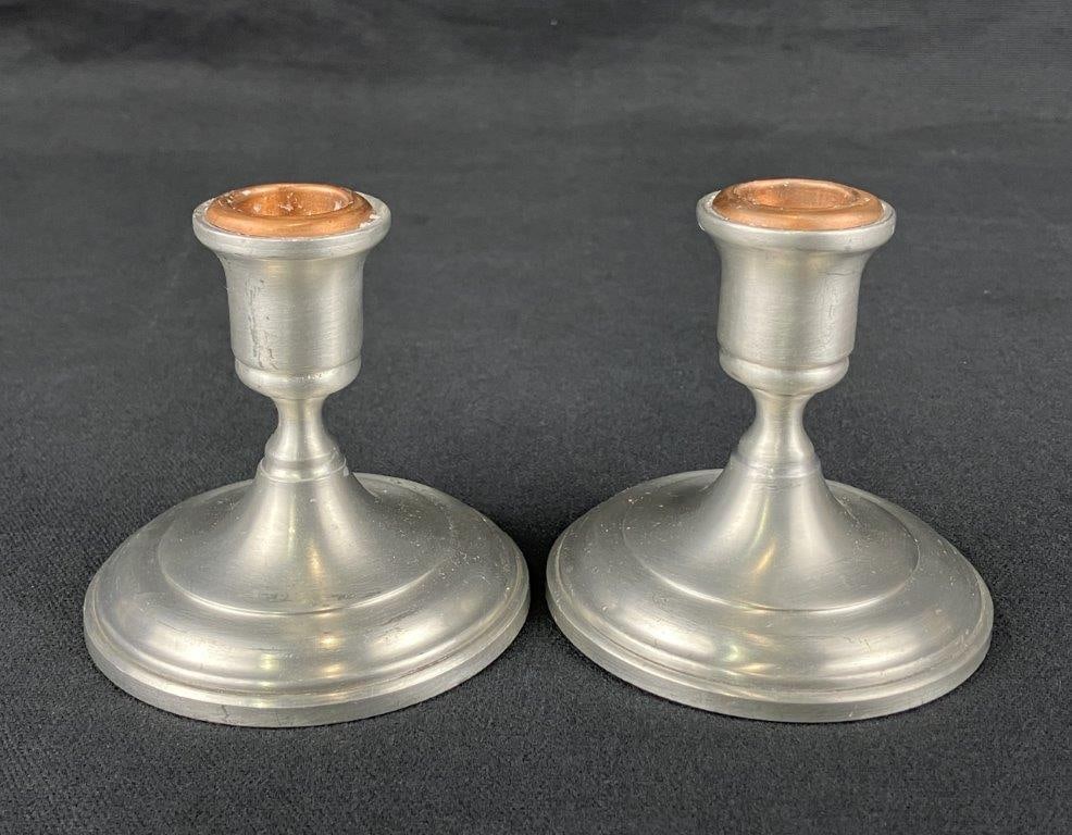Pair of Pewter Candlesticks: A pair of pewter candlesticks of simple, traditional form. One measures approximately 3 1/2″ H x 3 3/8″ in diameter. In good condition. 