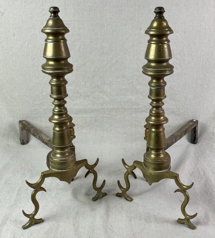 Brass Andirons: A pair of brass andirons featuring elegant, well-balanced forms and solid antique construction. The warm brass surface and classic silhouette provide refined hearthside appeal. Measure approximately