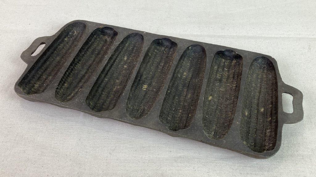 Cast Iron Cornbread Stick Pan: A cast iron cornbread stick pan with a well-developed surface patina. Measures approximately 12 3/4â€³ H x 5 5/8â€³ W x 3/4â€³ D. Shows general wear