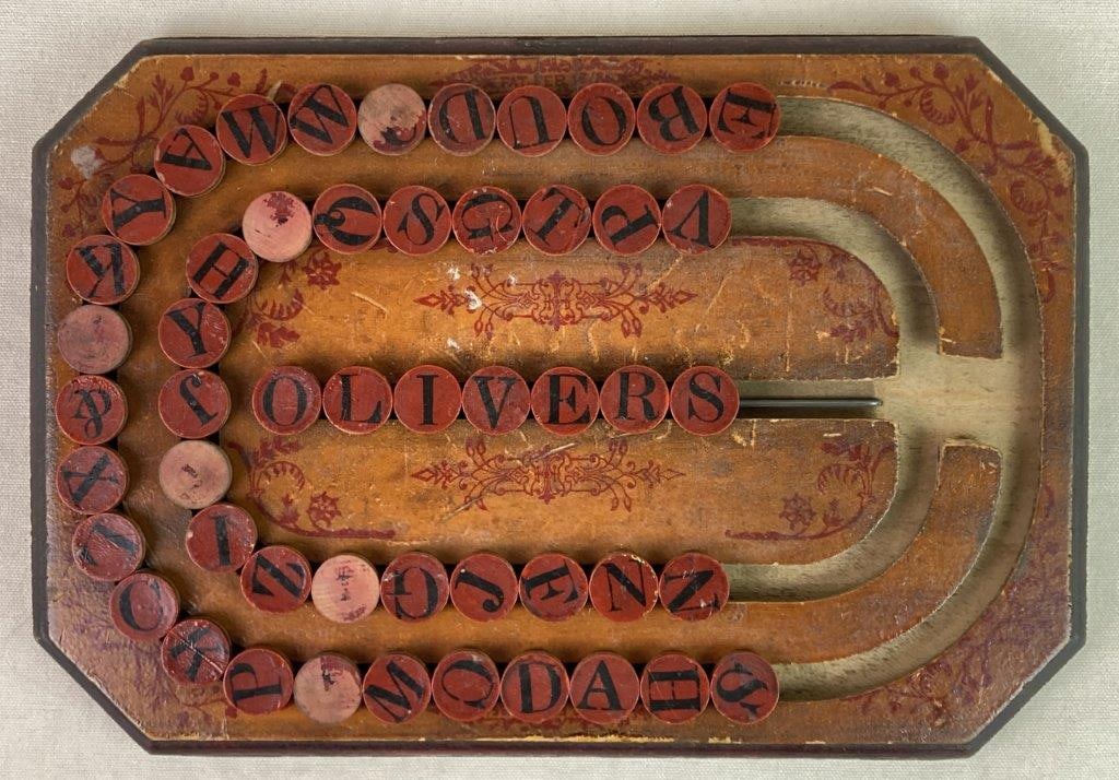 Wooden Spelling Board Game: An antique wooden spelling board game designed as an educational toy to help children learn spelling and word formation by sliding letter blocks along carved grooves. Decorated with red scrollwork