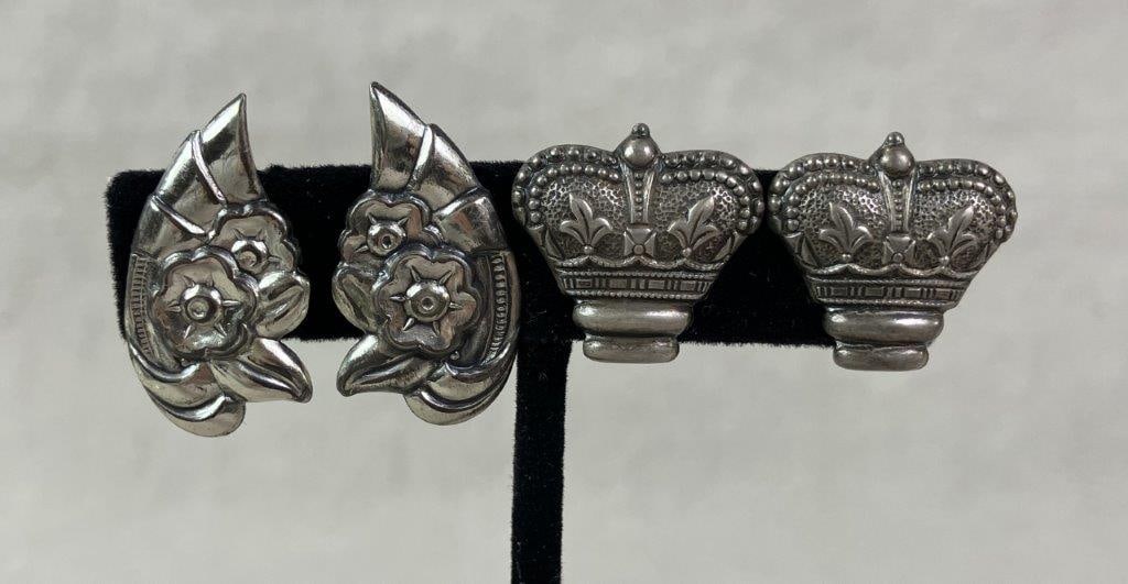 Two Pairs of Sterling Silver Screwback Earrings: Two pairs of sterling silver screwback earrings, including one pair designed with a regal crown motif and another featuring an elegant floral design, both rendered in an antique-inspired style. Both