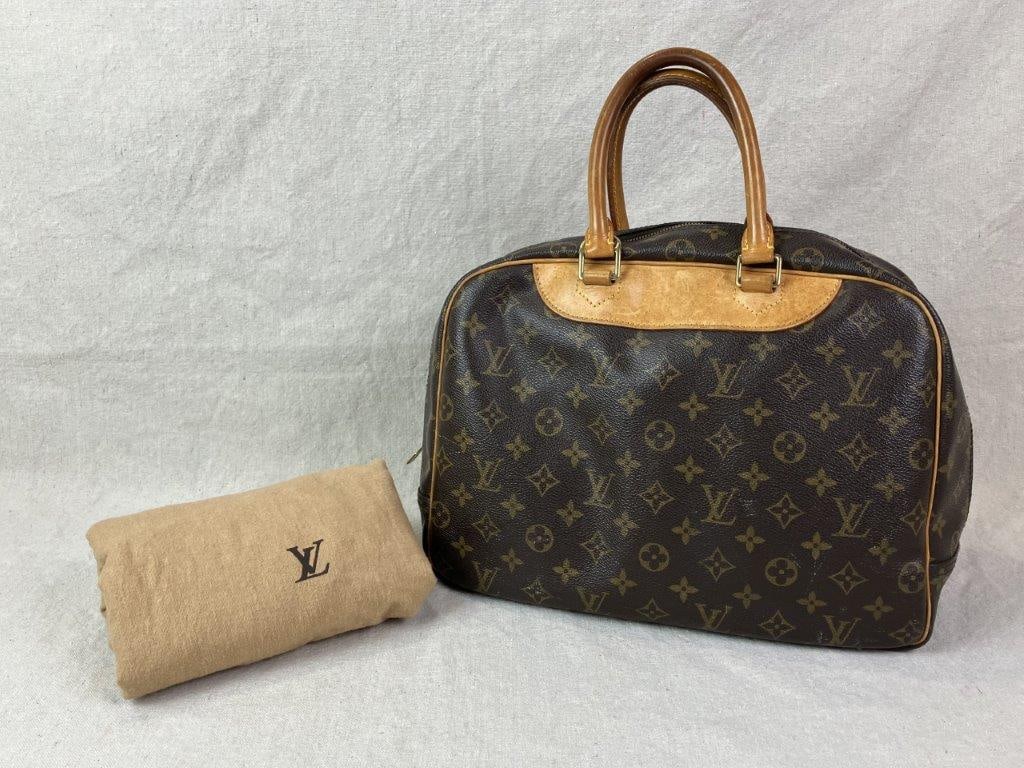 Louis Vuitton Deauville Vanity Bag: Louis Vuitton Deauville vanity bag crafted in the iconic monogram coated canvas with natural cowhide leather trim and dual rolled top handles. Features an exterior slip pocket and a well-appointed