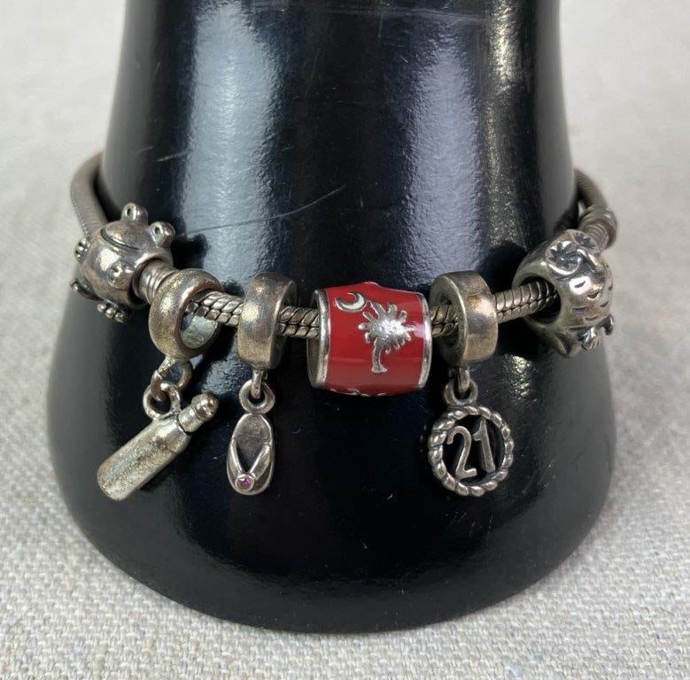 Pandora Sterling Silver Charm Bracelet: Pandora sterling silver snake chain bracelet decorated with assorted charms, including a red enamel charm featuring the South Carolina crescent moon and palmetto tree motif. Clasp marked 925 for