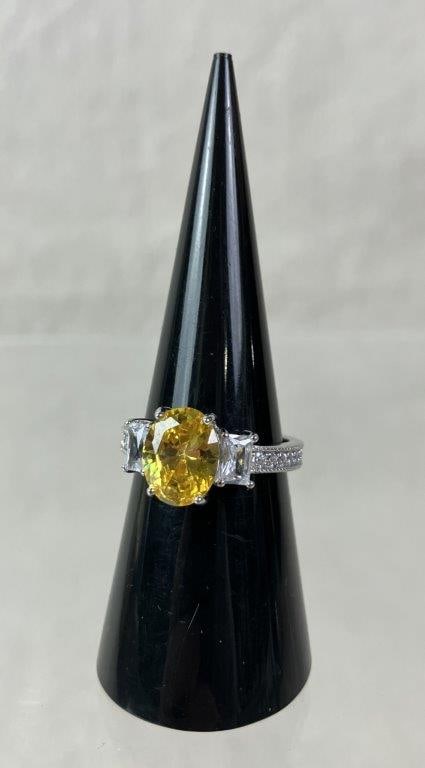 Yellow Sapphire and Sterling Silver Ring: Sterling silver ring centering a lab-grown oval-cut yellow sapphire, flanked by two baguette-cut clear faceted stones, all mounted within a polished sterling band. Ring size approx. 7. Total weight in