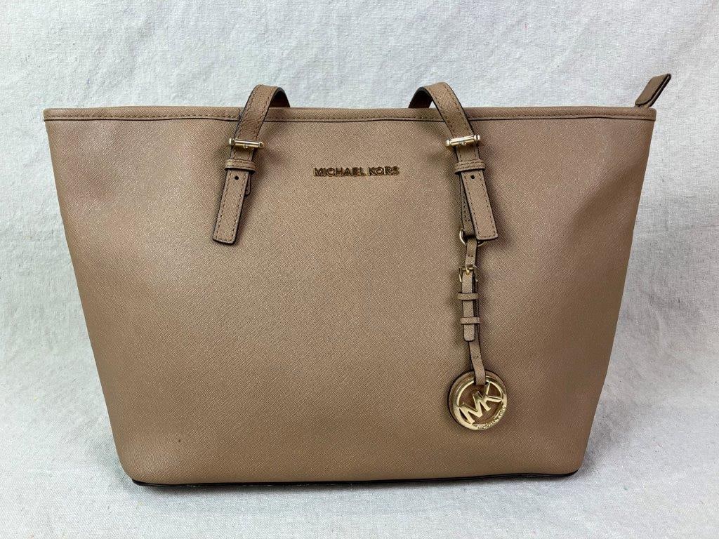 Michael Kors Jet Set Travel Tote: Michael Kors Jet Set Travel tote crafted in Saffiano leather with signature cross-hatch texture, featuring a top-zip closure and two adjustable buckle shoulder straps. Accented with gold-tone