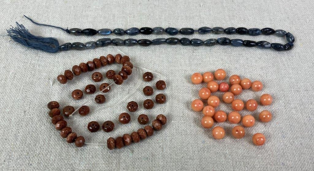 Lot of Gemstone and Coral Beads: Group comprising one strand of labradorite beads with frosted appearance and reflective sheen, one strand of faceted goldstone beads, and twenty-five loose round polished orange coral beads. Various s