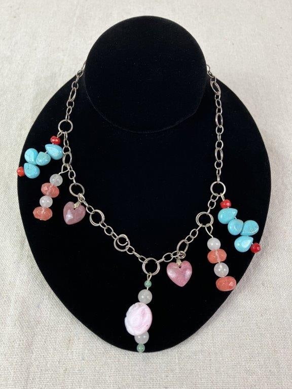 Sterling Silver Beaded Necklace: Sterling silver necklace composed of ring links and accented with a teardrop-shaped turquoise, a round pink bead carved with a rose design, smaller red accent beads, and heart-shaped stone charms.