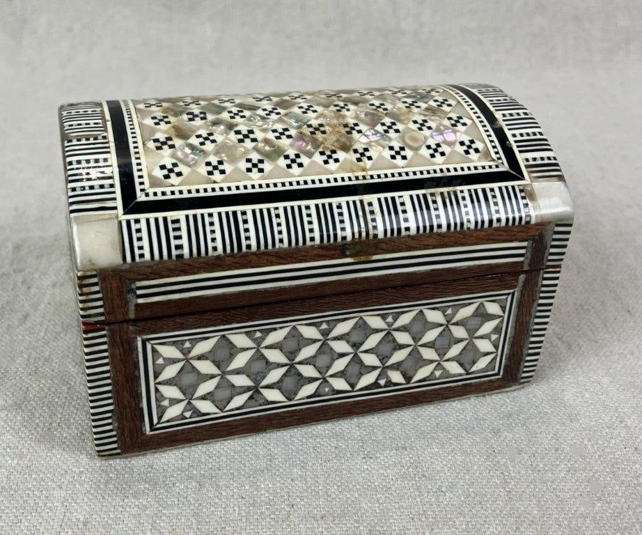 Mother-of-Pearl Inlay Middle Eastern Trinket Box: Artisan-crafted box featuring traditional Middle Eastern design elements with intricate mother-of-pearl marquetry inlay set against warm wood accents. Interior lined in red velvet. Measures approx. 2