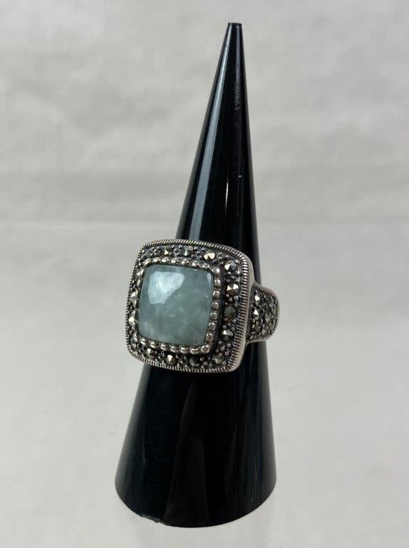 Sterling Silver, Jade, and Marcasite Ring: Sterling silver ring marked for silver content, featuring a central square jade cabochon framed by a setting adorned with a multitude of marcasite stones. Mounted to a robust sterling band. Ring size