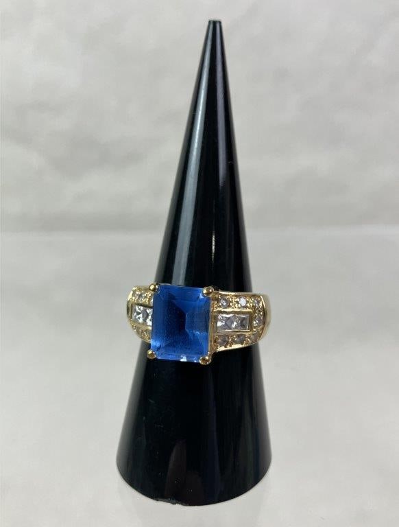 Sterling Silver Cocktail Ring: Sterling silver ring with gold finish or gold plating, marked 925 to interior, featuring a central emerald-cut blue stone (possibly spinel-style or synthetic sapphire) in a raised setting with simple