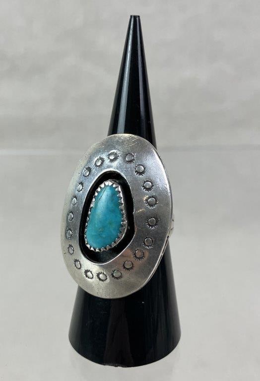 Native American Sterling Silver and Turquoise Ring: Native American ring of robust and substantial statement form, featuring a central natural turquoise cabochon framed by a sterling silver punchwork border and mounted to a streamlined band. Tested for