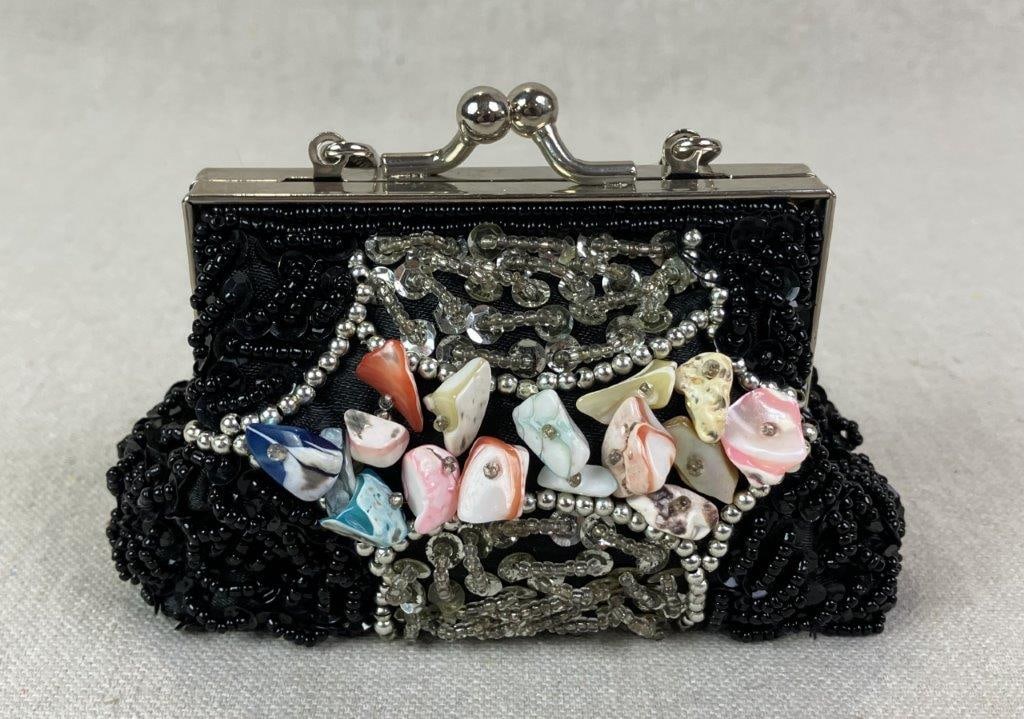 Cadari London Beaded Black Satin Coin Purse: Petite evening coin purse by Cadari London crafted in black satin and adorned with black and silvertone beading, silvertone sequins, and central faux shell embellishments. Features silvertone frame
