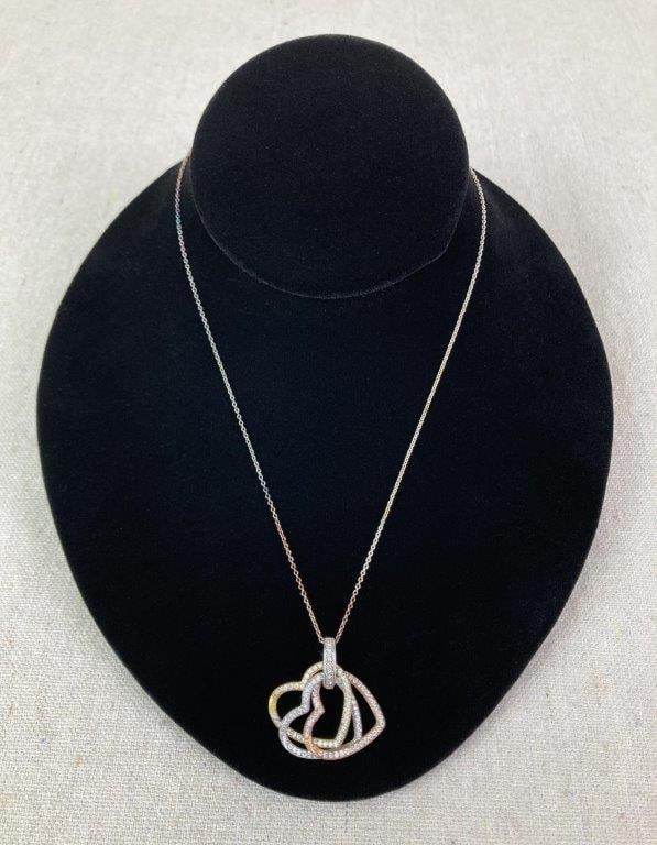 Sterling Silver and Gold Vermeil Three-Heart Necklace: Sterling silver necklace featuring three interlocking open heart motifs, two accented with gold vermeil, and adorned with cubic zirconia or clear faceted stones arranged across the surfaces. Marked