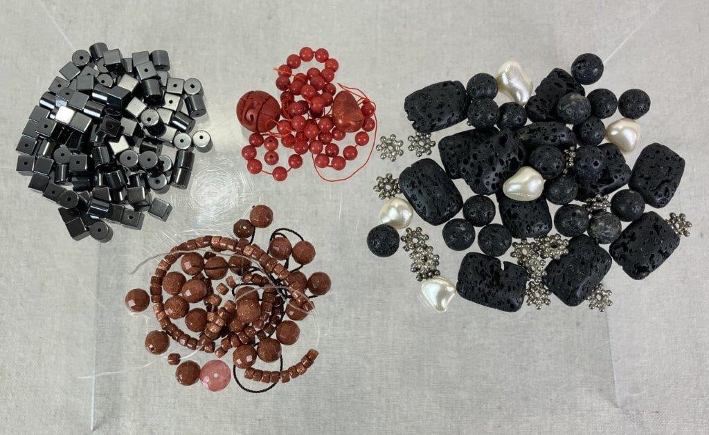 Assortment of Mixed Stone and Decorative Beads: Assorted grouping of beads including goldstone, one cinnabar example, coral beads, hematite, basalt or lava rock, and faux pearls in varied shapes and finishes. One lava stone measures approx. 7/8" H