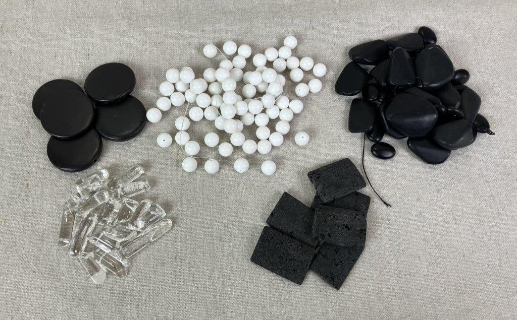 Assortment of Mixed Stone Beads: Assorted grouping of mixed stone beads including polished quartz crystal beads, black coral, polished black basalt stones, and white marble or white jade beads. One round black basalt stone measures