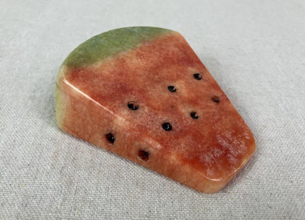 Carved Stone Watermelon Slice: Hand-carved alabaster stone figure in the form of a watermelon slice, featuring red and green coloration with polished finish and painted seed details. Measures approx. 3 3/4" H x 3 1/4" W x 1 1/2"