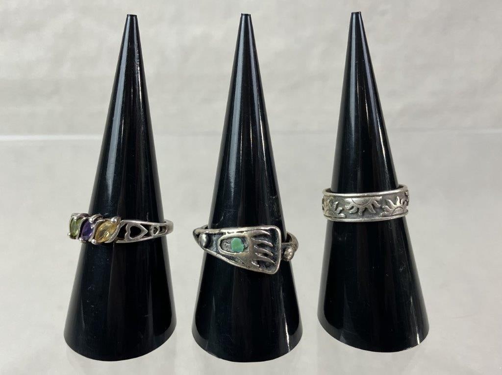 Three Sterling Silver Rings: Group of three sterling silver rings including a handmade Native American example with a bear paw motif set with inlaid green turquoise (ring size approx. 8.75), a wide band ring with repeating sun sy