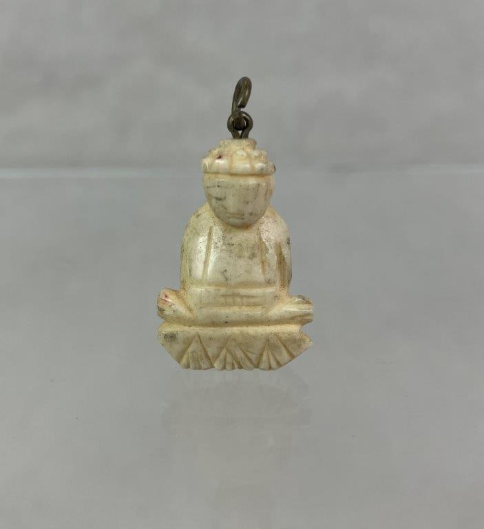 Carved Bone Seated Buddha Pendant: Carved bone pendant depicting a seated Buddha in meditative pose, rendered with serene facial features and carefully incised detailing to define the figure and robes. Measures approx. 1" H x 3/4" W.