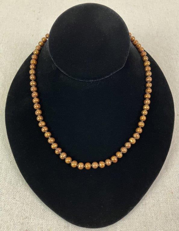 Chocolate Pearl Necklace: Elegant single-strand pearl necklace composed of distinctive chocolate-toned pearls displaying soft luster and natural surface variation characteristic of pearls. Necklace measures approx. 16" L. In