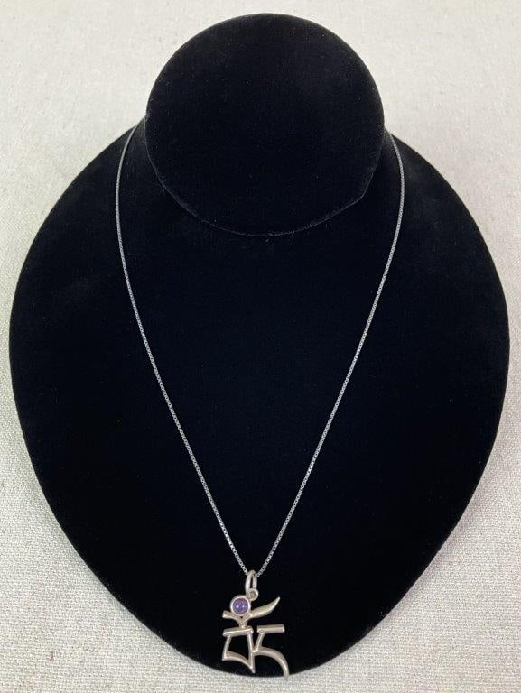 Sterling Silver and Amethyst Om Symbol Necklace: Sterling silver necklace featuring a pendant symbolic of Buddhist Tibetan script with the Om meditation symbol, centered by an amethyst cabochon. Marked 925 to reverse. Chain measures approx. 16" L.