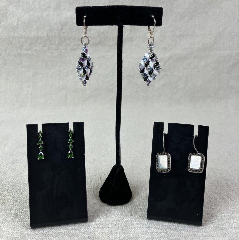 Three Pairs of Sterling Silver Dangle Earrings: Grouping of three pairs of sterling silver dangle earrings including one pair with intricate beaded detailing, one pair accented with multiple peridot stones, and one pair featuring a simple design