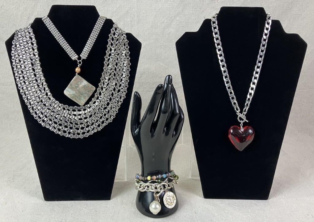 Silvertone Statement Jewelry Assortment: Collection of silvertone statement jewelry including three necklaces and three bracelets in bold, fashion-forward designs. Highlights include a necklace featuring a large acrylic heart pendant
