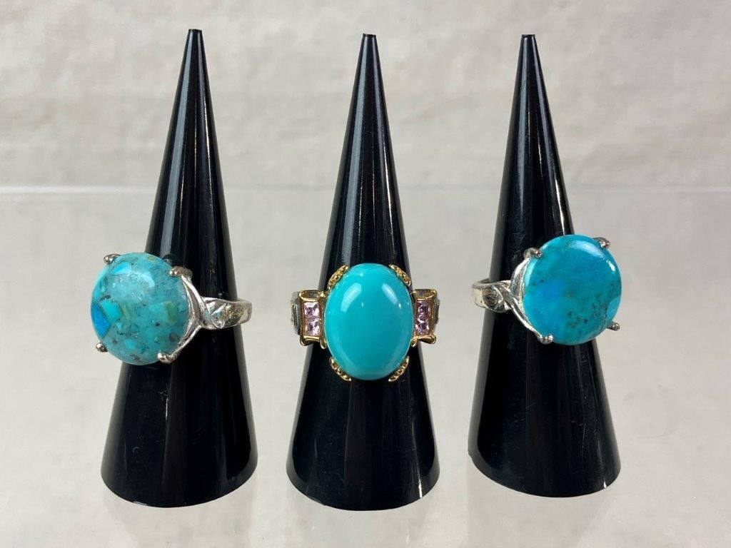 Three Silver Turquoise Statement Rings: Group of three turquoise statement rings including two sterling silver examples set with turquoise cabochons in simple prong-set bands (ring sizes approx. 5.5 and 6.5), and one silver and gold-tone