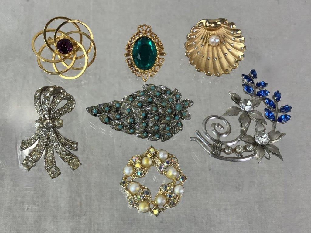Seven Vintage Brooches: Collection of seven vintage brooches including rhinestone-set examples and faux pearl designs. Highlights include a feathered silvertone brooch accented with faux turquoise cabochons and a goldtone
