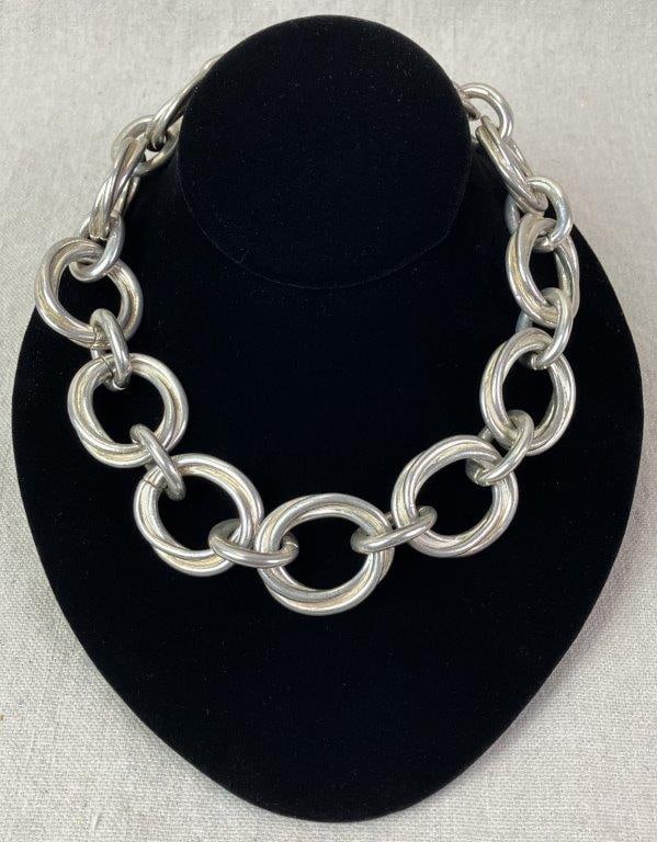 Silvertone Statement Necklace: Chunky silver tone statement necklace composed of interlocking open circular links in a bold articulated design, finished with a toggle clasp bearing the maker's logo. Rich silver tones throughout.