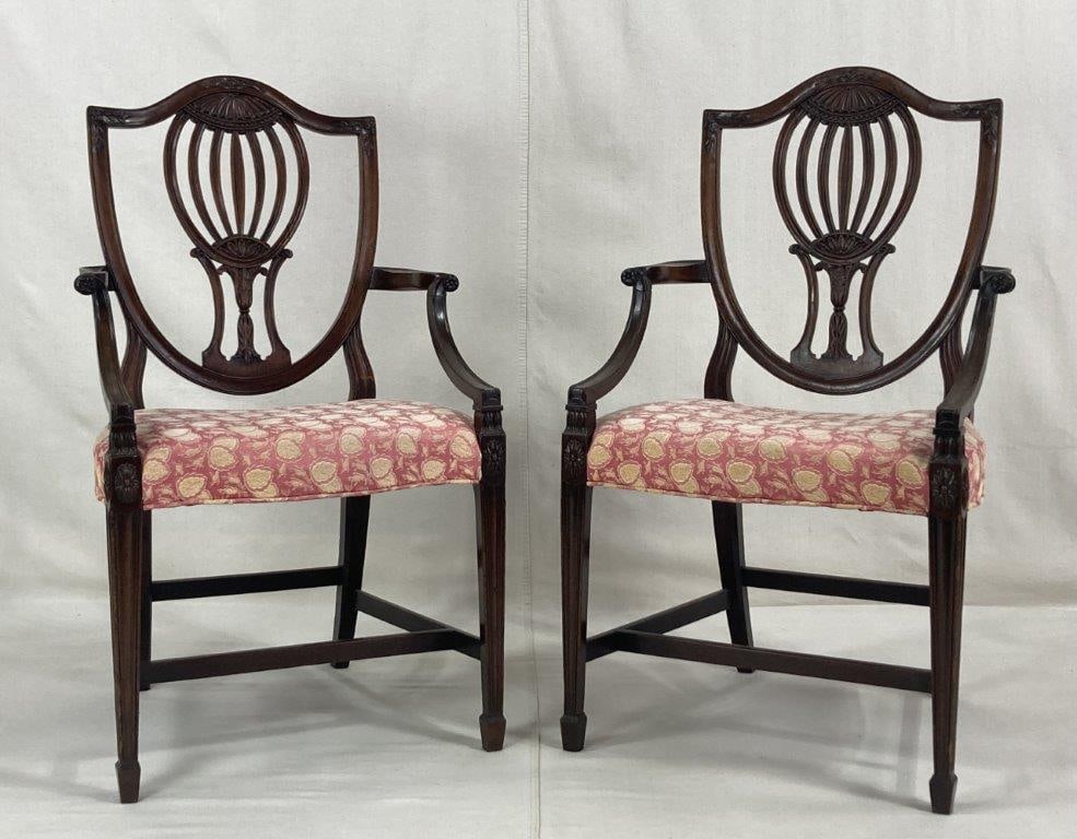 Pair of Georgian Shieldback Armchairs: Circa 1800, a refined pair of George III-style armchairs crafted from rich mahogany with a beautiful aged patina. Each chair features an open shieldback with intricate carvings that flow into