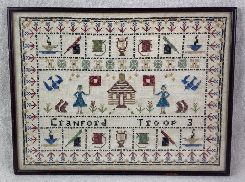 Girl Scout Troop Needlepoint Sampler: An antique needlepoint sampler commemorating the history and activities of "Cranford Troop 3." The composition features a central log cabin motif flanked by Girl Scout figures holding red flags, all