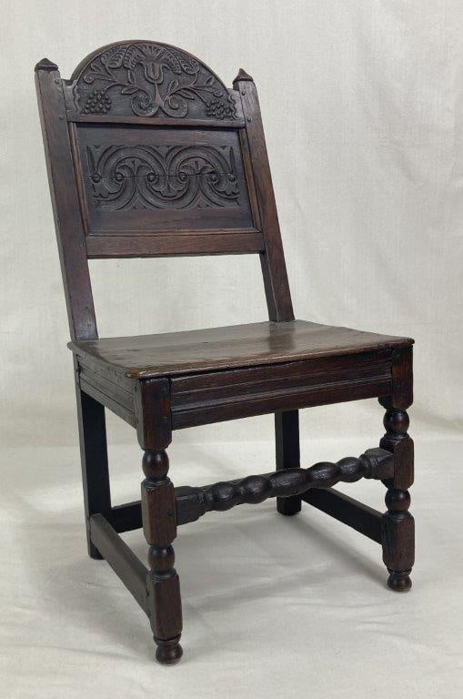 William and Mary Period Carved Oak Chair, Circa 1680-1690: English William and Mary period chair crafted in carved oak with a rich dark surface and traditional form typical of the late 17th century. The backrest is decorated with expertly carved tulip and