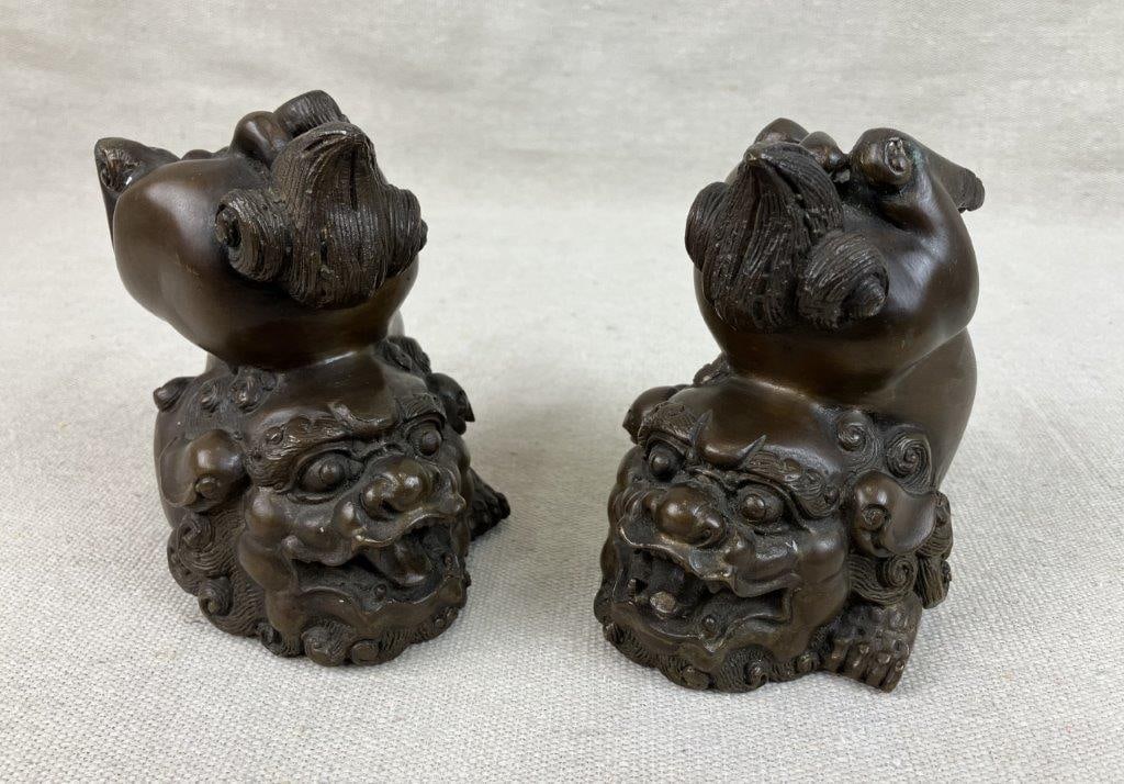Pair of Bronze Foo Dogs: A protective and expertly sculpted set of cast bronze guardian lions traditionally used as symbols of prosperity and safe-keeping. These figures exhibit the intricate detailing and fluid forms