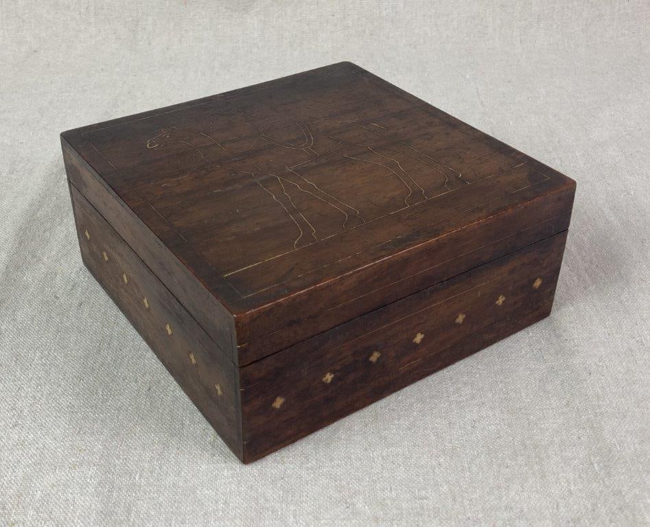 Early 20th Century Anglo-Indian Wood Box: A mahogany wood box with a hinged lid, decorated with bone inlaid details including a camel on the lid and small decorative accents encircling the sides of the box. The surface retains a warm patina,