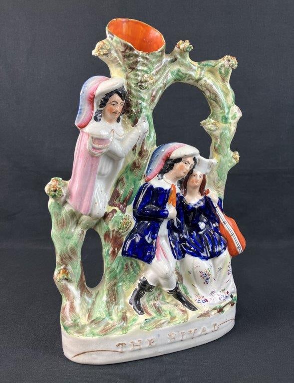 Staffordshire The Lover's Rival Spill Vase: Depicts two lovers beneath a verdant tree in traditional English dress, the female figure playing a stringed musical instrument while a rival or onlooker peers from around the tree. Decorated in