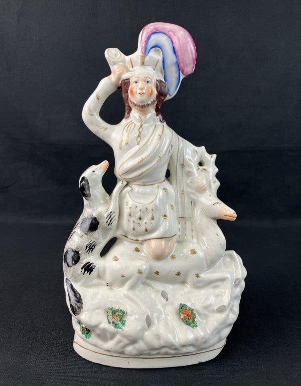 Staffordshire Hunter Figurine: Depicts a hunter or Highlander in a plumed cap accompanied by his hunting dog and capturing a stag. Hand-painted details, produced in the Staffordshire pottery district of England, with an expressive