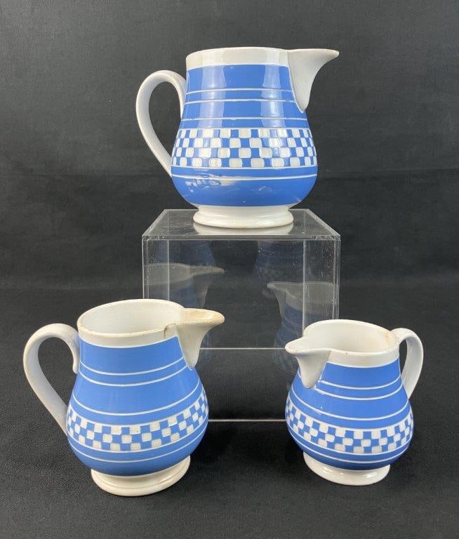 Three Graduated Checker Ware Jugs, Villeroy & Boch: Late 19th to early 20th century examples from Dresden, Germany, featuring elegant, rounded forms decorated in soft blue and white checker patterns. Each bears the maker's mark on the base. The