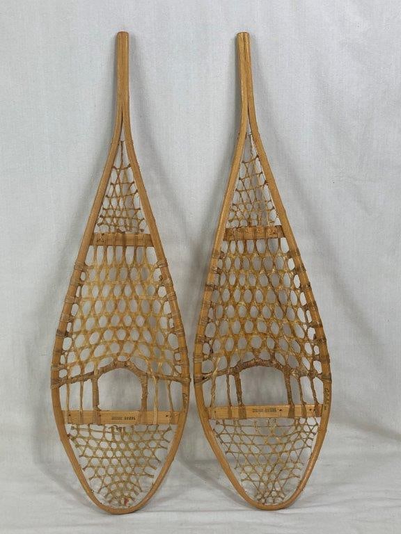 Pair of Snowshoes: A pair of traditional-style snowshoes crafted from soft honey-toned wood with classic lattice webbing. The frames are marked with the Cabela's brand name, representing a blend of functional outdoor