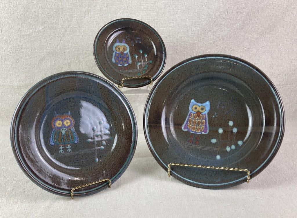 Studio Pottery Stoneware Plates: Three studio pottery stoneware plates, each featuring a teal-glazed rim with bronze and blue variegated glazes to the surface. Each plate is adorned with a multi-colored stylized owl motif, and two of