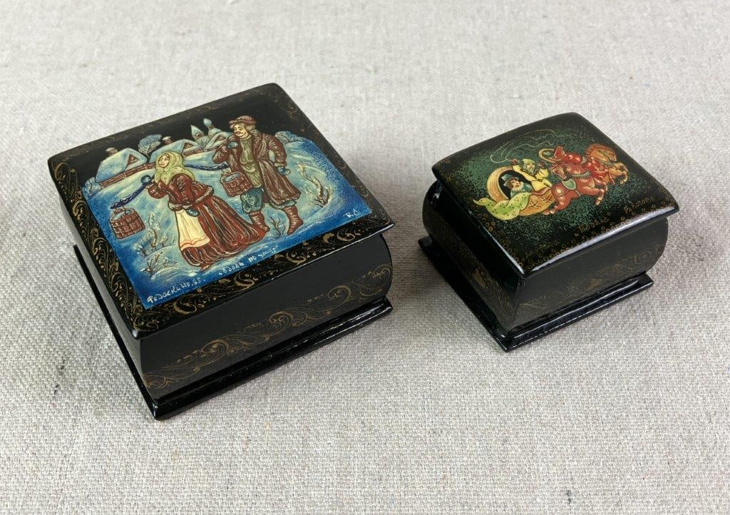 Two Hand Painted Russian Lacquer Box: One displaying a man driving a carriage amid the clouds with an elegant lady passenger, inspired by Russian fairy tales. Another with a man and women in a snowy landscape. Black lacquer exterior with